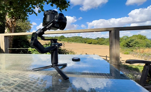 FeiyuTech SCORP Mini روی یک میز مشرف به یک مزرعه